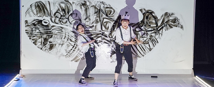two children standing in front of a doodle wall