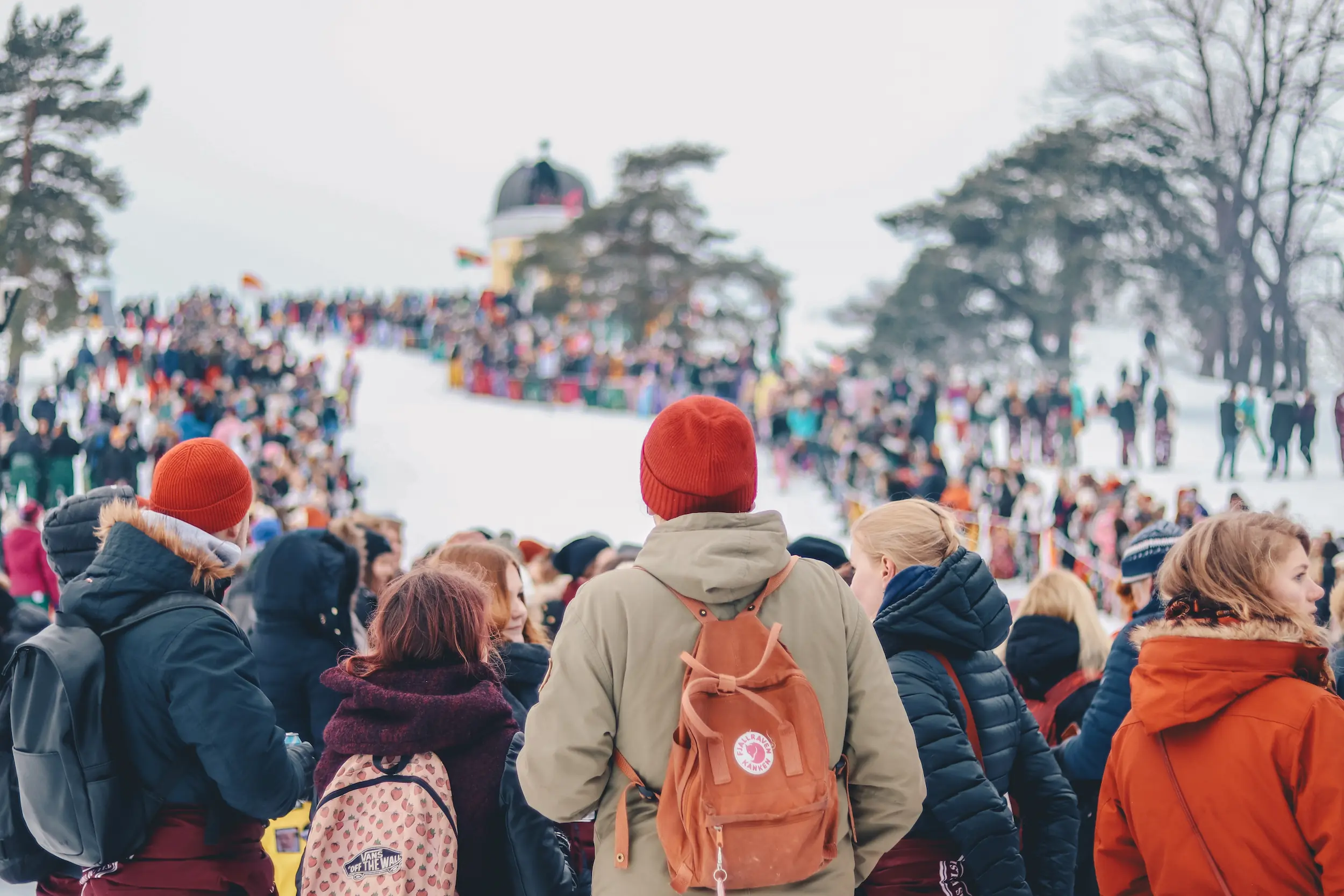 A large group of people hiking on a snowy hill.