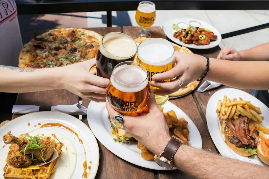Pizzas on table-top with arms cheering three bear glasses